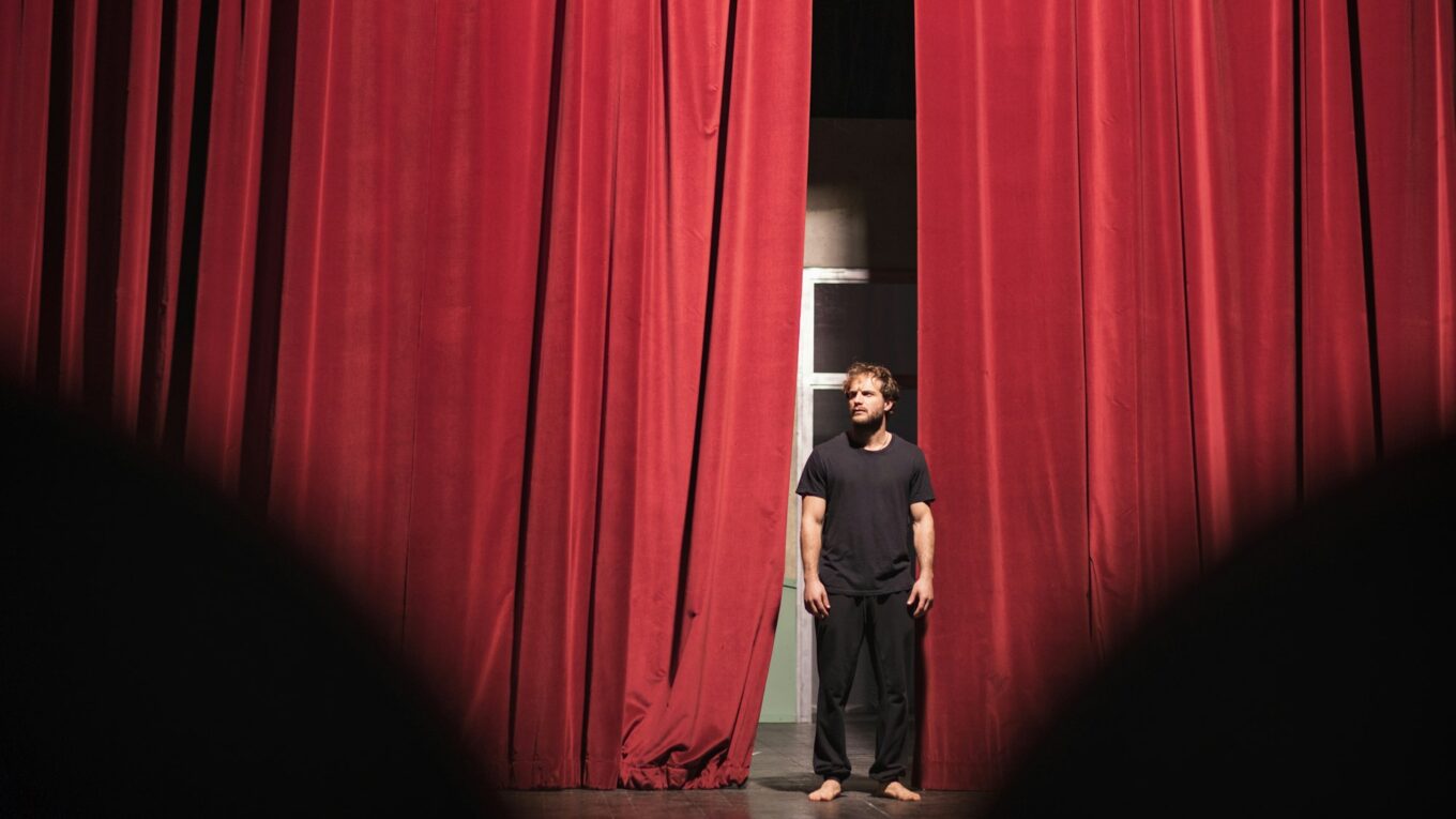 Barefoot actor standing on theatre stage