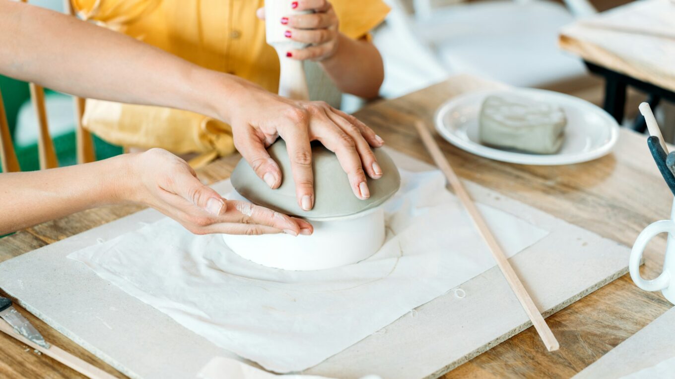 Ceramic workshop. Group of friends crafting a ceramic plate.