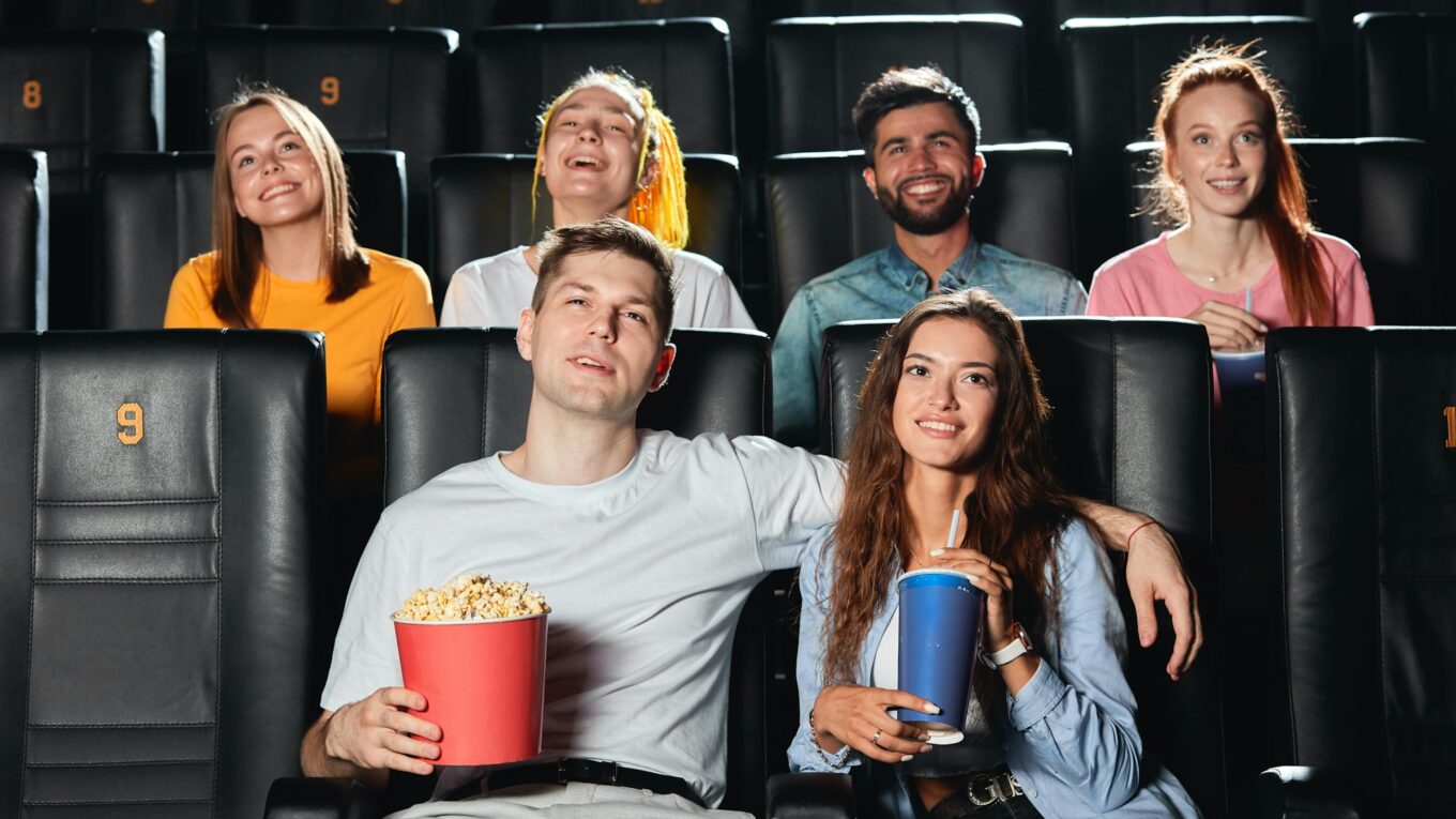 Happy couple eating popcorn , drinking cola while watching film