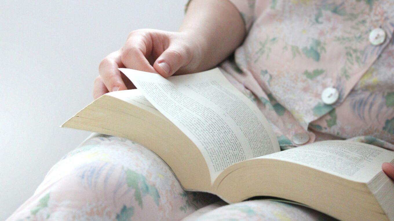 Woman reading a large fiction novel book in her hands