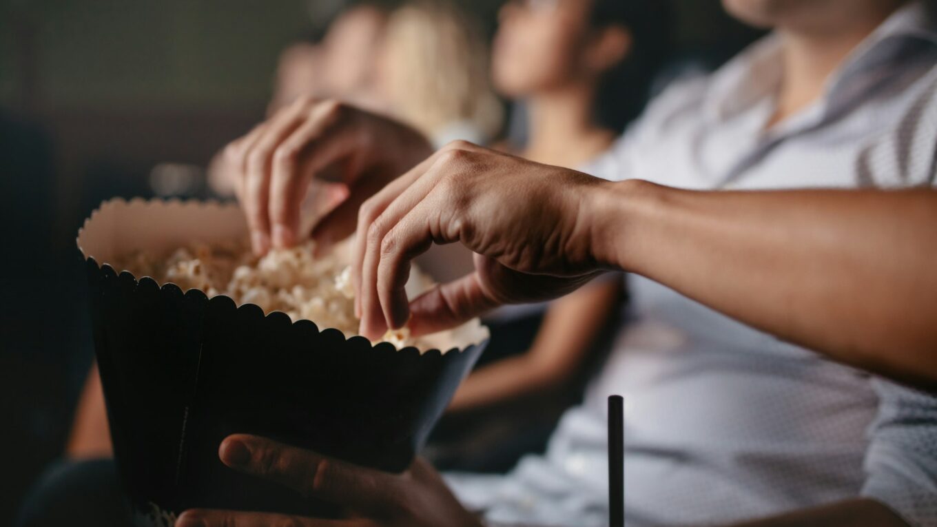 Young people eating popcorn in movie theater