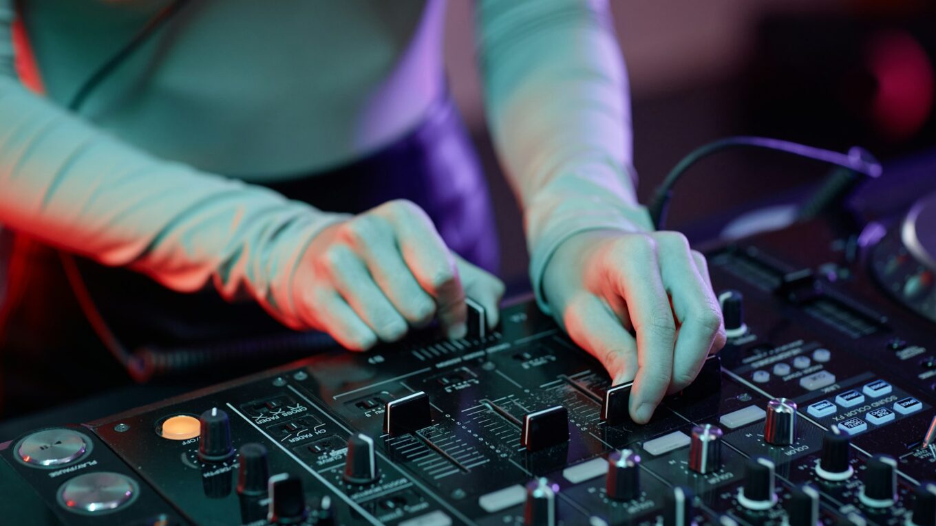 Young woman as DJ making music tracks at mixer table